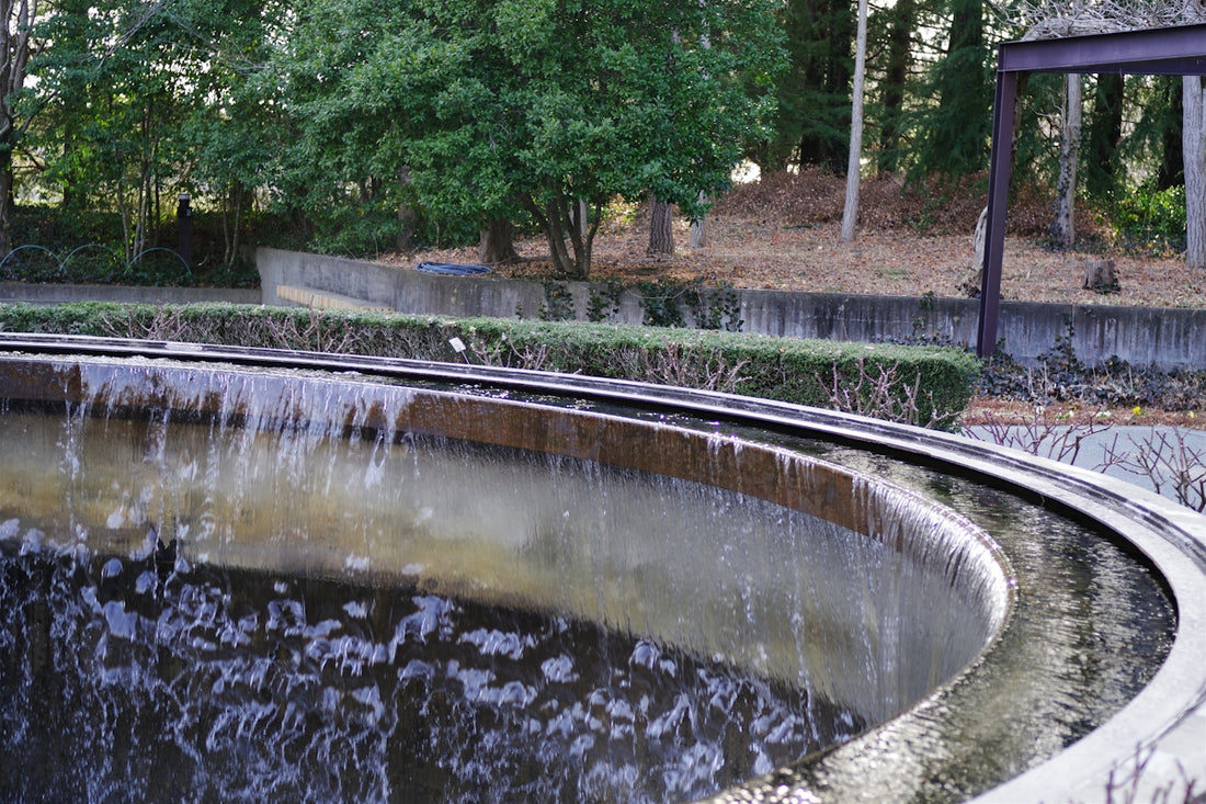Water cascades over the edge of a circular fountain.